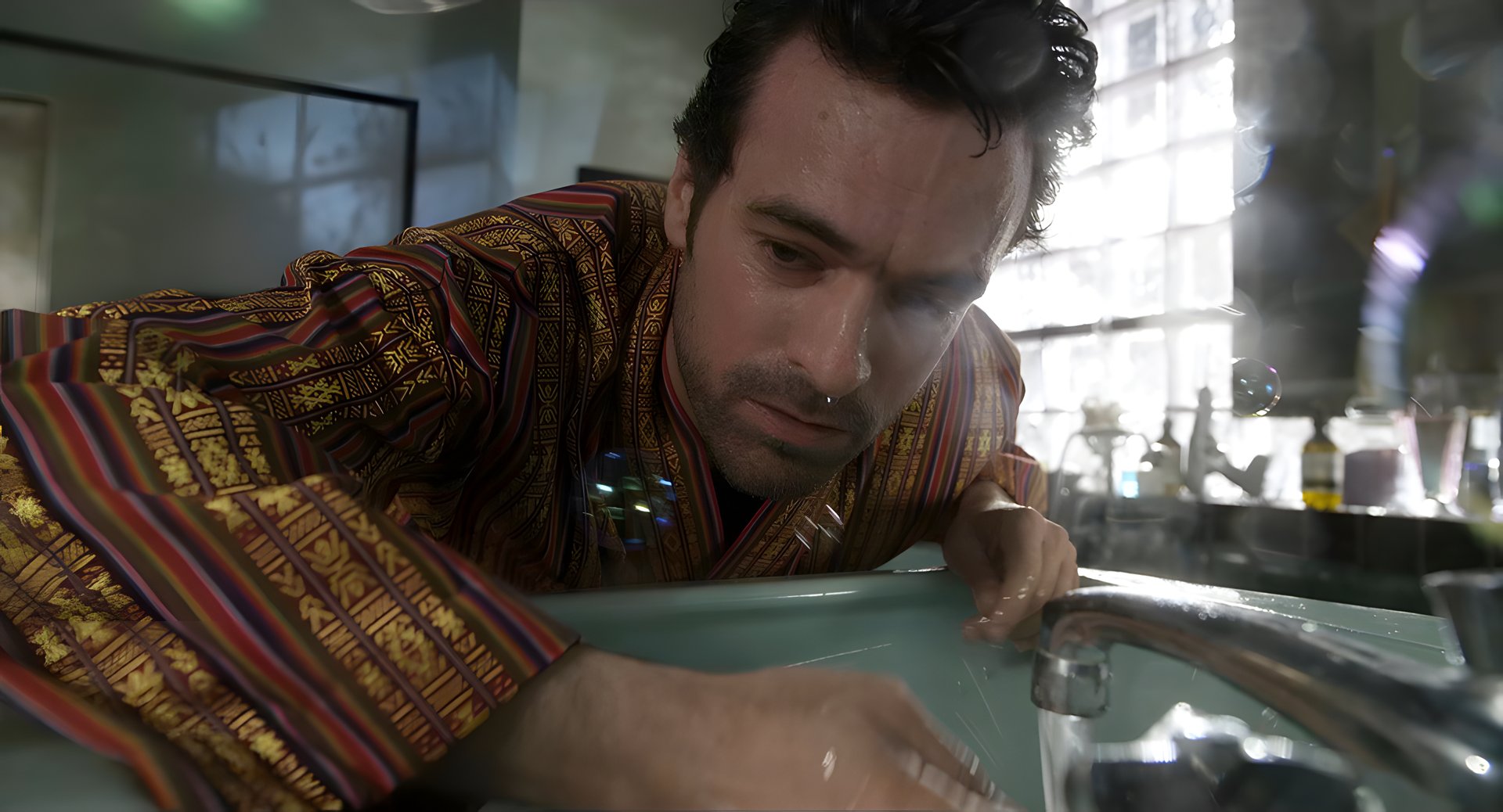 A sweating man hunched over a sink