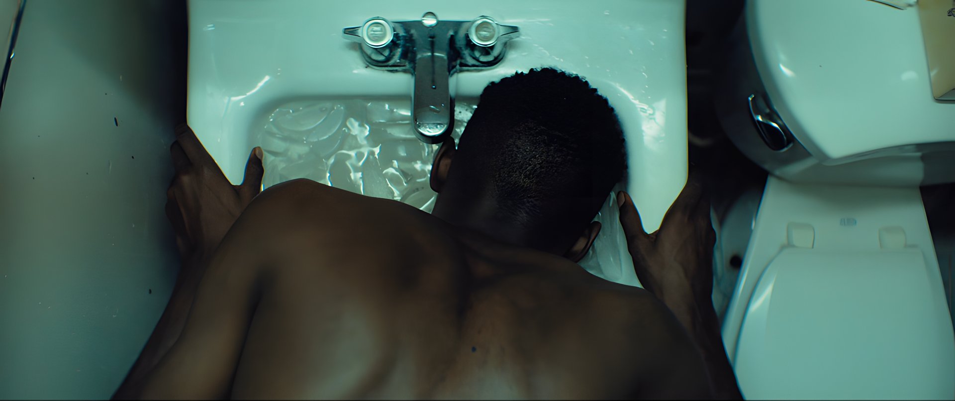 A man plunging his head into a sink of cold water