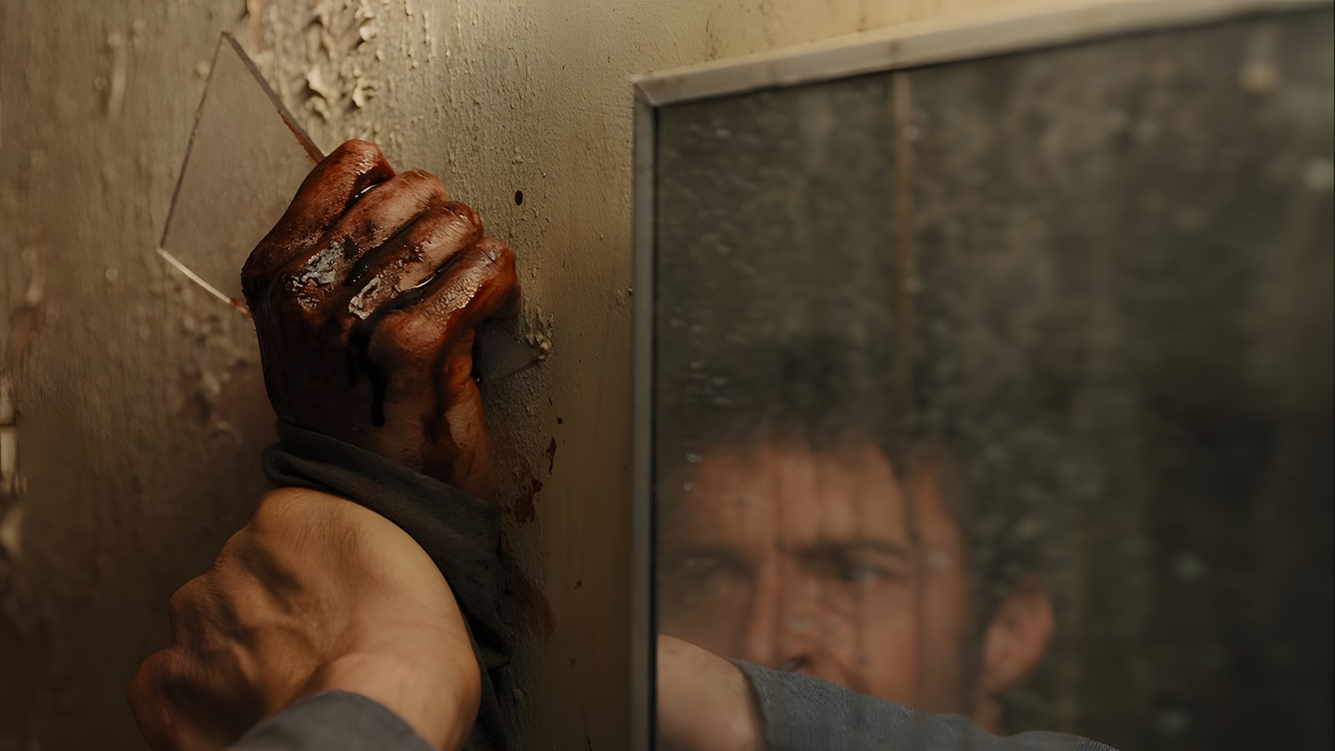 A bloodied hand against a cracked mirror
