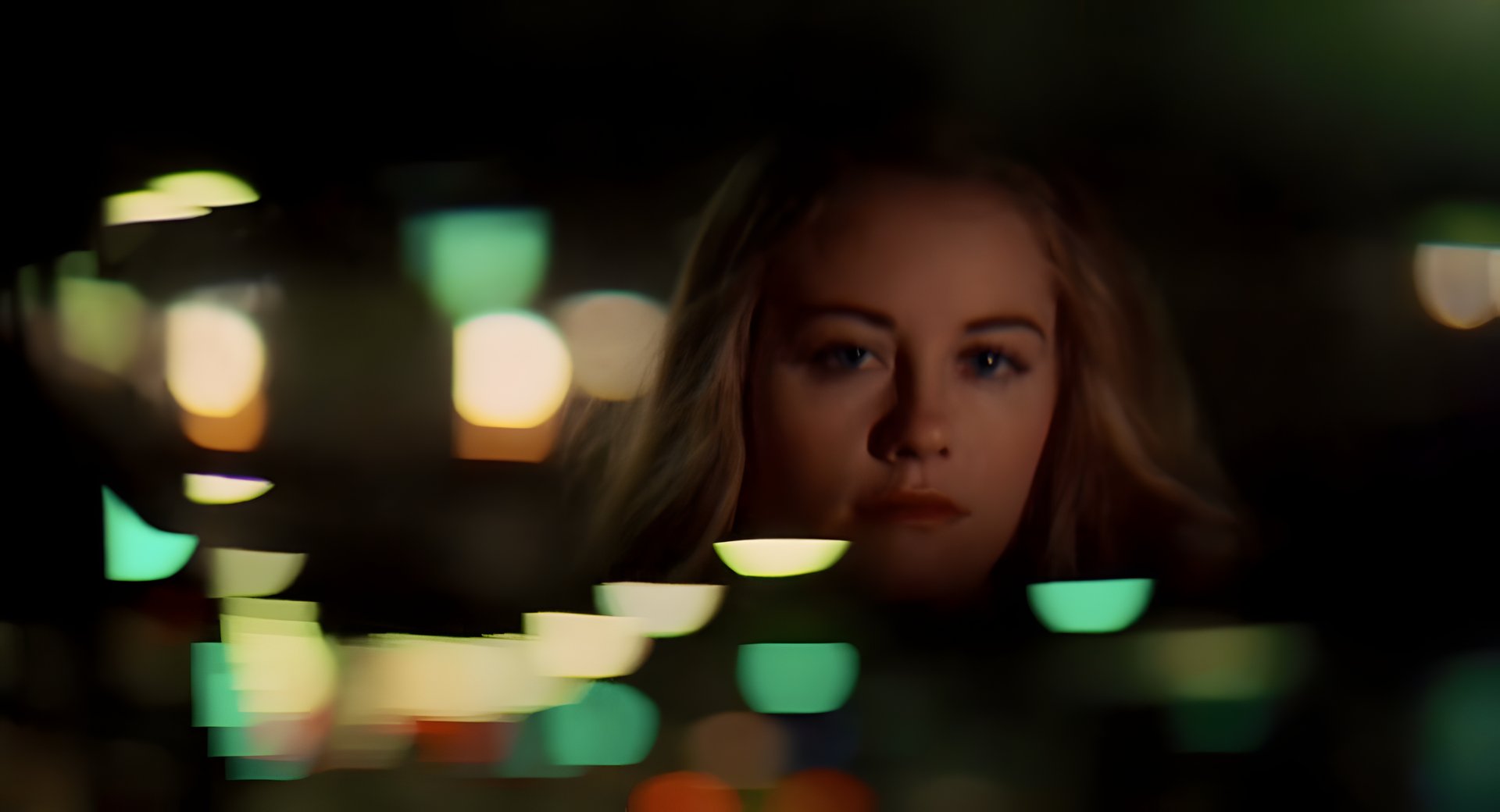 A woman's face lit by passing lights in a car