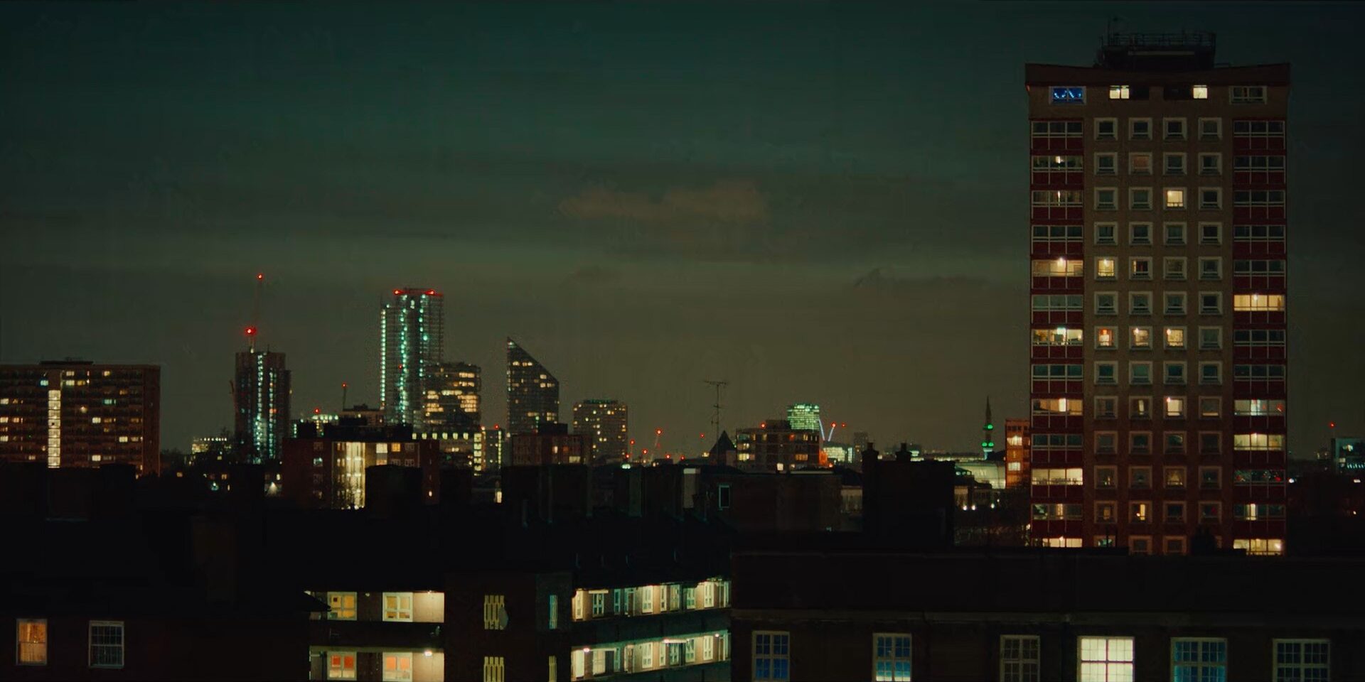 A tower block at night, windows lit
